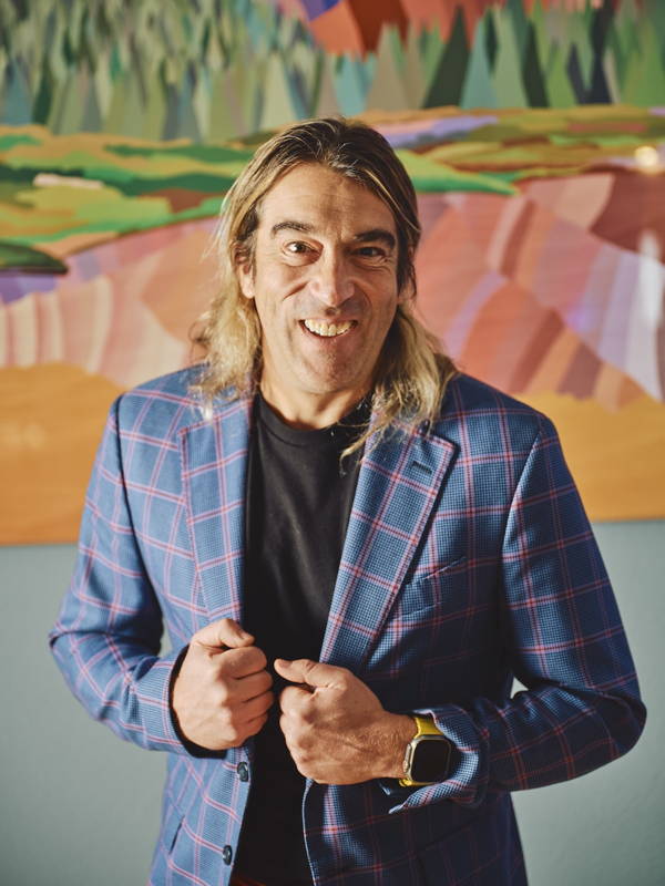 Topher Straus in a blue checked jacket with The Grand Traverse painting